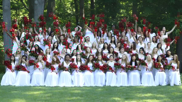 Un grupo de alumnas de The Madeira School está en el bosque sosteniendo rosas rojas.