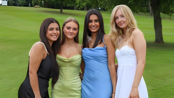 Cuatro alumnas de The Mary Erskine School están en el parque sobre un césped frente a unos árboles.