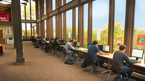 Puesto de trabajo con varios estudiantes en la computadora en una gran sala de The Orme School con vista a la naturaleza.