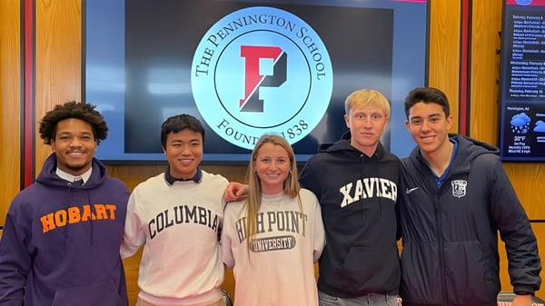Un grupo de cinco estudiantes está frente al logo de The Pennington School en la pared.