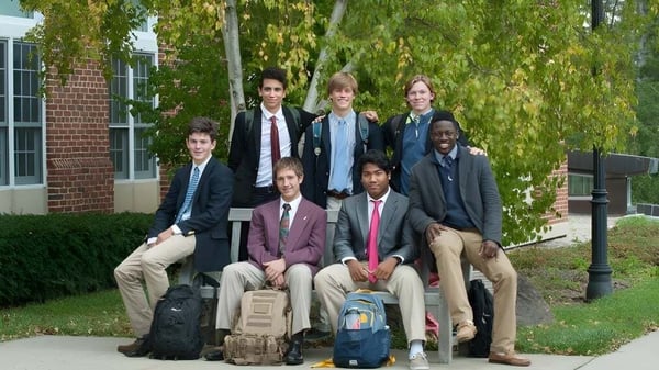 Un grupo de estudiantes se encuentra en un prado frente a un edificio en el campus de The Salisbury School.