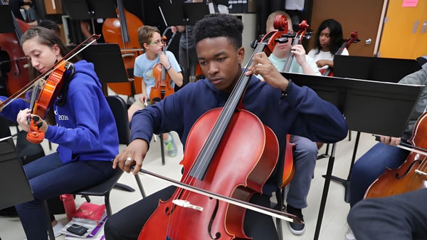 Un estudiante de la The Storm King School toca concentrado un gran violonchelo rojo en un ensayo de música.