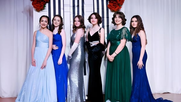 Un grupo de seis jóvenes mujeres en elegantes vestidos de noche en un evento nocturno en el campus de The Webb School.
