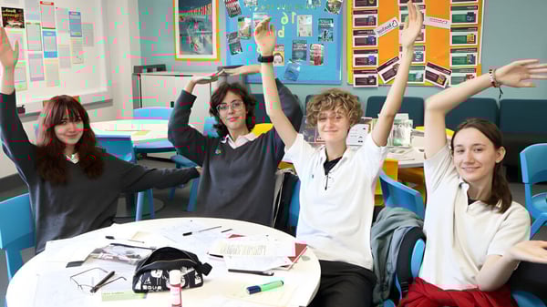 Estudiantes de The Wren School levantan las manos en el aula durante una actividad de clase.