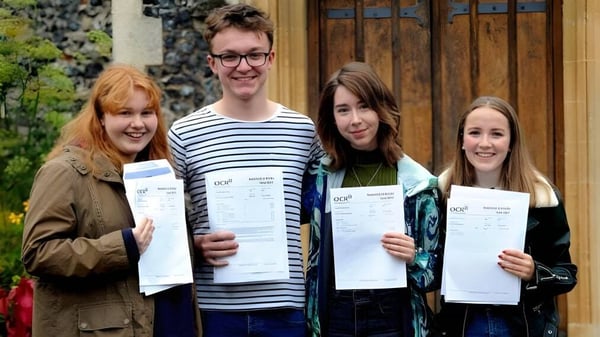 Cuatro estudiantes de la Thetford Grammar School están afuera y muestran orgullosamente sus diplomas.