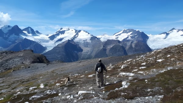 Una persona está de pie en un camino rocoso con montañas nevadas al fondo en el terreno de la Thomas Haney Secondary School.