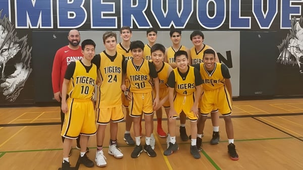 Un grupo de jóvenes jugadores de baloncesto de Thornhill Secondary School posan frente a un banner de Timberwolves en la cancha de baloncesto.