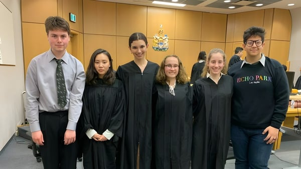 Estudiantes de Thornhill Secondary School están vestidos de forma formal frente a un escudo.
