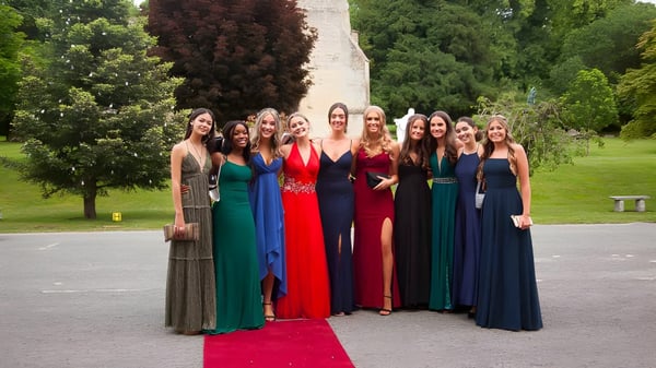 Un grupo de jóvenes mujeres en vestido formal está en un evento nocturno en el campus del Thornton College en el parque.