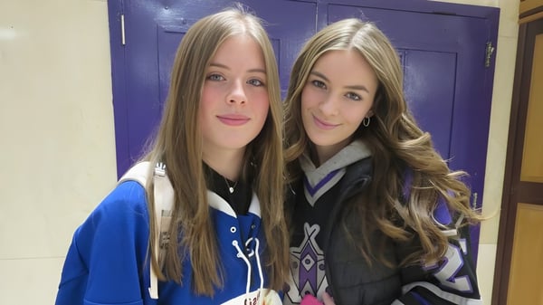 Dos alumnas de la Thousand Islands Secondary School están frente a una puerta morada y sonríen a la cámara.