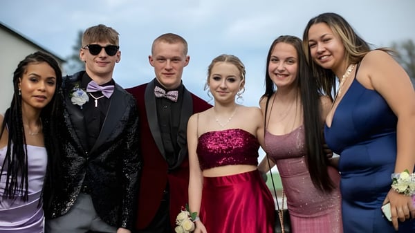 Un grupo de personas bien vestidas posan juntas frente a un fondo borroso en el terreno de la Three Rivers Christian School.
