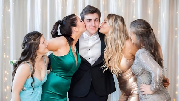 Un grupo de estudiantes de la Tilton School posan en un evento formal con un niño en el centro.