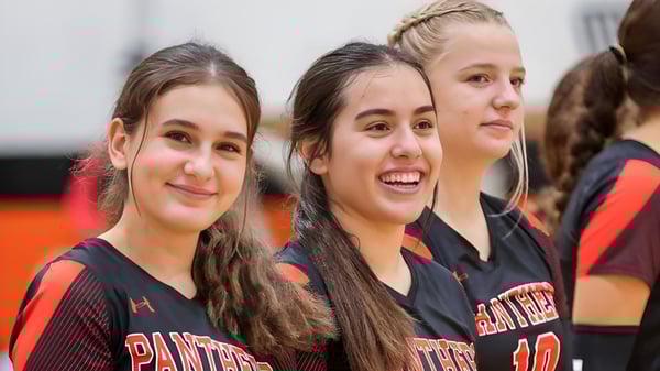 Un grupo de alumnas de TMI Episcopal lleva uniformes deportivos y posan juntas en un entorno deportivo.