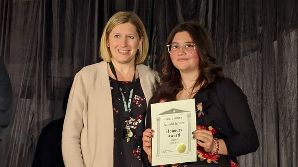 Dos mujeres están juntas sosteniendo un certificado en el campus de Tofield School.