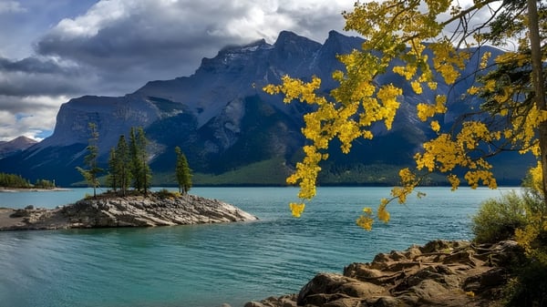 Vista de un lago tranquilo con montañas y hojas de otoño cerca de Tofield School.