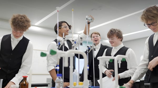 Un grupo de estudiantes de la Tonbridge School está en una sala con equipos e instrumentos científicos de fondo.