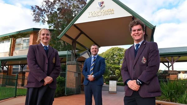 Tres estudiantes en uniforme escolar están de pie frente al edificio de la Toowoomba Anglican School.
