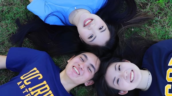 Tres estudiantes de la Torrance High School están acostadas sonriendo en la pradera y mirando a la cámara.