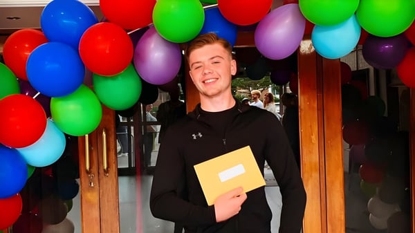 Una persona con una camiseta negra está frente a una exhibición de globos coloridos en el campus de la Trafalgar School.