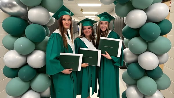 Un grupo de jóvenes mujeres en vestidos y sombreros de graduación verdes posan para la foto de graduación en el campus de la Transcona Collegiate.