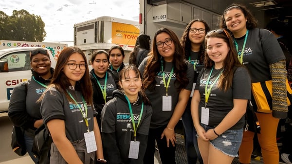 Un grupo de estudiantes de la Tree of Life Christian School está en camisetas verdes y negras frente a vehículos al aire libre.