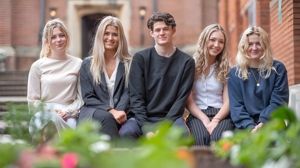 Un grupo de cinco estudiantes se sienta junto en una escalera en el campus del Trent College.