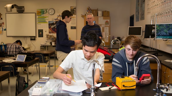 Un grupo de estudiantes está sentado en un aula de la Tri-Cities Prep Catholic High School y trabaja en conjunto.