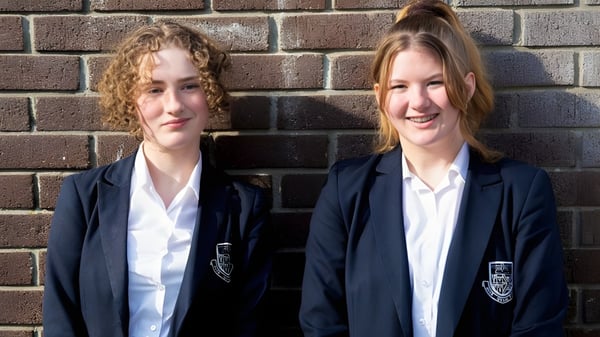 Dos alumnas de Truro School están frente a una pared de ladrillo.