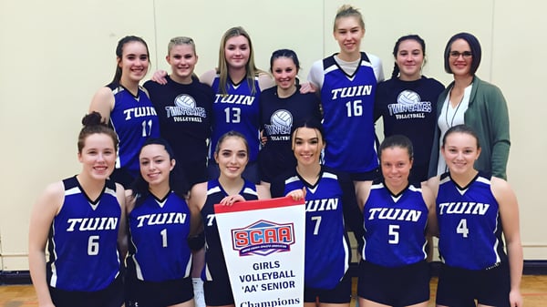 Un grupo de jugadoras de voleibol de la Twin Lakes Secondary School posando juntas en el gimnasio.