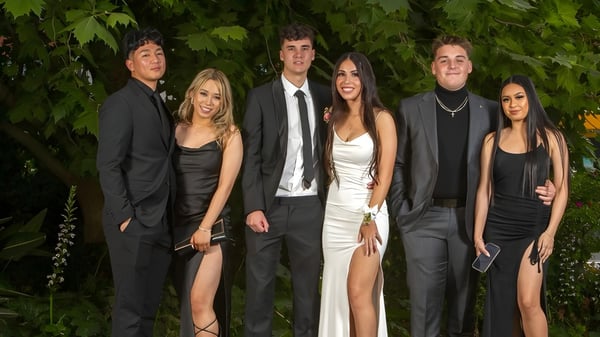 Un grupo de estudiantes bien vestidos se encuentra en el área verde exterior de la Underdale High School.