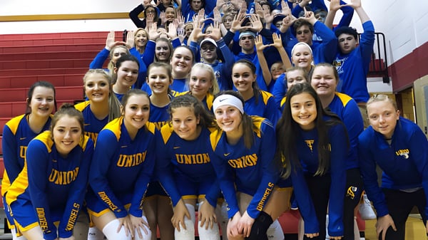 Un grupo de estudiantes de la Union High School está en uniformes azules y amarillos juntos en un gimnasio.