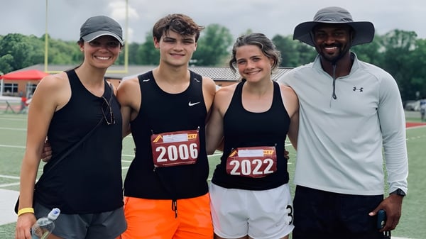 Cuatro atletas están juntos en el campo de deportes de la Unity Christian High School durante un evento deportivo.