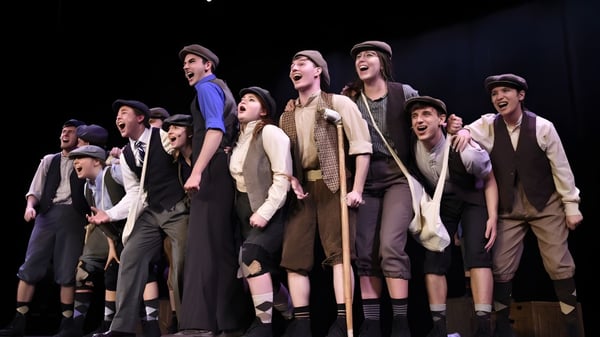 Estudiantes de la Unity Christian High School en trajes de teatro posan en un escenario con iluminación dramática.