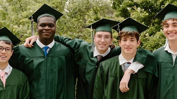 Un grupo de graduados está de pie en togas verdes al aire libre en el campus de la University Lake School.