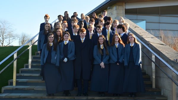 Un grupo de estudiantes de la Uppingham School está en la escalera frente a un edificio con fachada de vidrio.