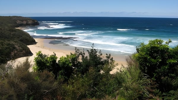 Un paisaje costero idílico con playa y mar frente al fondo de un cielo despejado.