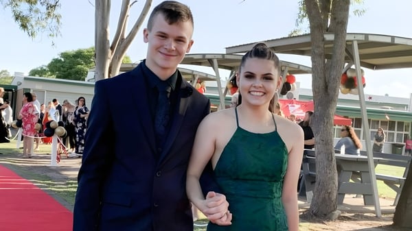 Una joven pareja está junta en la alfombra roja en el terreno de la Urangan State High School.