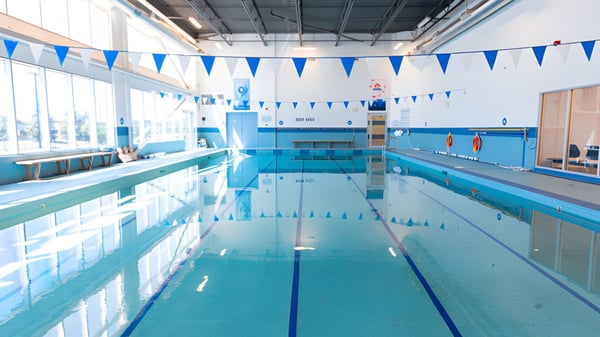 La piscina cubierta de la Urban International High School con banderas azules y blancas en el techo y grandes ventanas para luz natural.