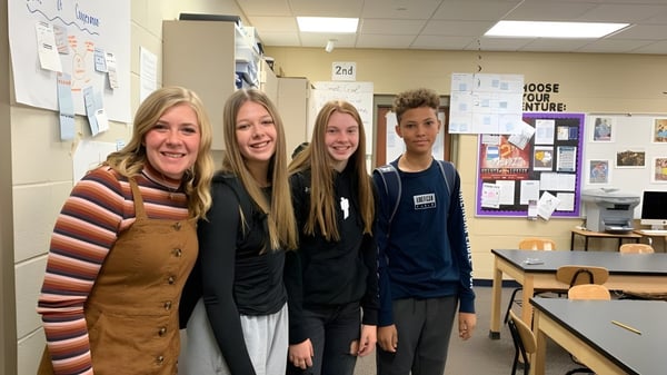 Cuatro estudiantes están juntas en un pasillo de Urbandale High School frente a carteles educativos.