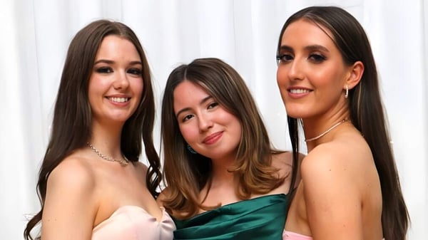 Tres alumnas del Ursuline College Sligo posan juntas frente a un fondo blanco en ropa formal.