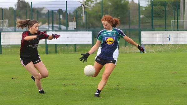 Dos alumnas del Ursuline College Sligo corren en ropa deportiva en un campo de césped con instalaciones deportivas al fondo.