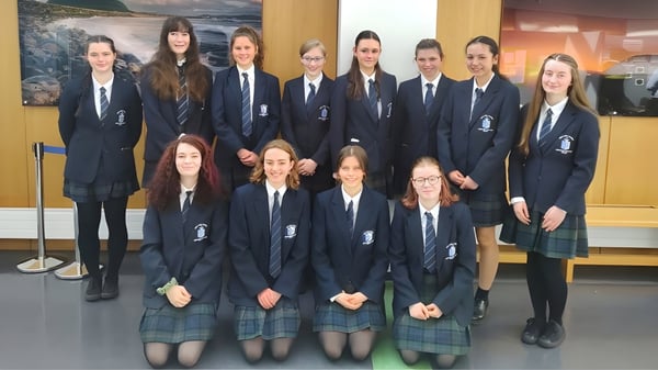 Un grupo de alumnas y alumnos del Ursuline College Sligo posan con un paisaje de fondo.