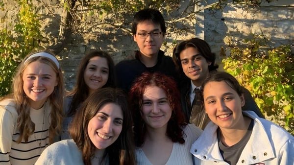 Un grupo de estudiantes posa frente a un muro de piedra en el terreno del UWC Atlantic College.