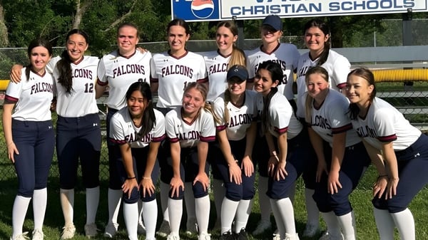 Un grupo de estudiantes de la Vacaville Christian School posan en sus uniformes de softbol frente al letrero de la escuela.