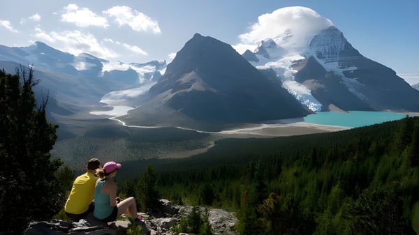 Dos personas están sentadas en una roca y disfrutan del paisaje montañoso con un lago cerca de la Valemount Secondary School.