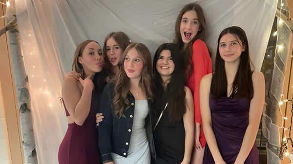 Un grupo de estudiantes del Vankleek Hill Collegiate Institute posan frente a una cortina blanca.