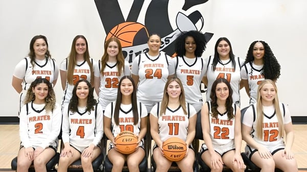 Un grupo de jóvenes alumnas en camiseta de baloncesto posan frente a una pared con un gran logo de baloncesto en el Ventura County Community College District.
