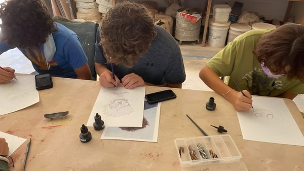 Estudiantes de la Verde Valley School se sientan juntos en una mesa y trabajan en una actividad creativa de dibujo.