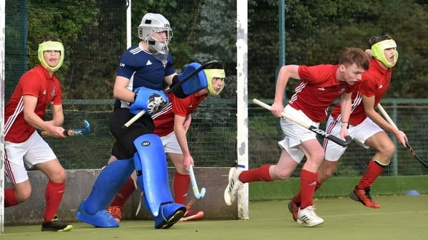 Estudiantes de la Villiers School juegan un partido de hockey sobre césped en un campo rodeado de árboles.