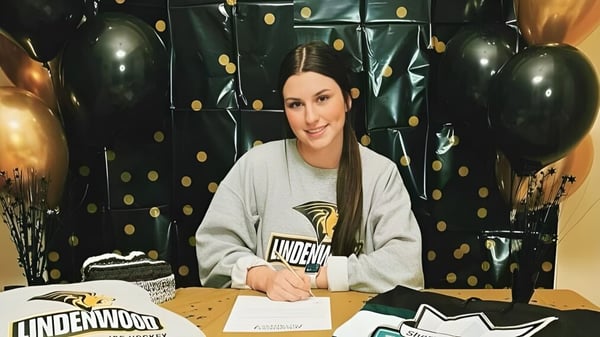 Una estudiante de la Vimy Ridge Academy está sentada en una mesa con globos negros y dorados en el fondo.